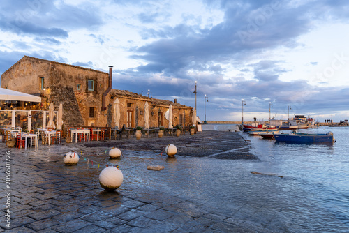 Evening light over the historic stone buildings and fishing boats at Marzamemi harbor in Sicily