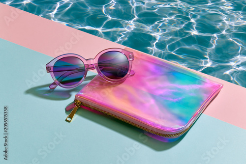 Jelly aesthetic sunglasses and iridescent cosmetic pouch by sparkling poolside with pastel colors translucent textures and dreamy summer vacation vibe