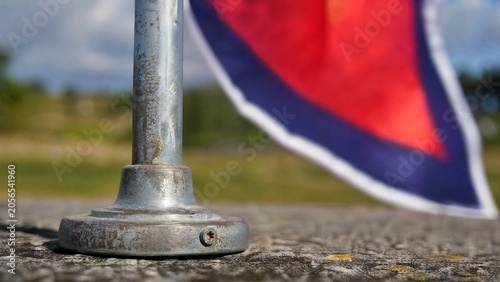 Cuadro en lienzo Close-up of metal flagstick base showing weathered texture against vibrant flag