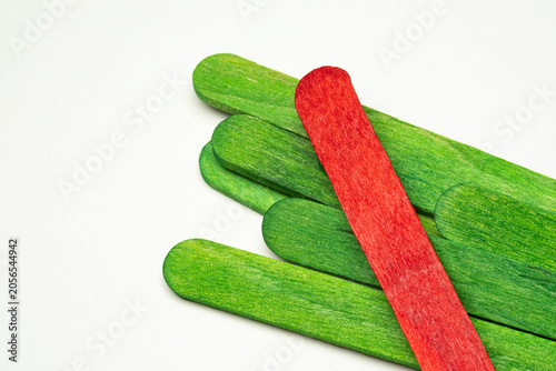 Close-up view of green and red wooden craft sticks arranged on white background. Bright colorful materials commonly used for DIY projects, arts and crafts, education and creative design concepts.