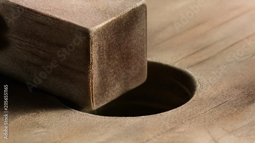 Photos A square wooden peg attempts to fit into a round hole, showing worn edges