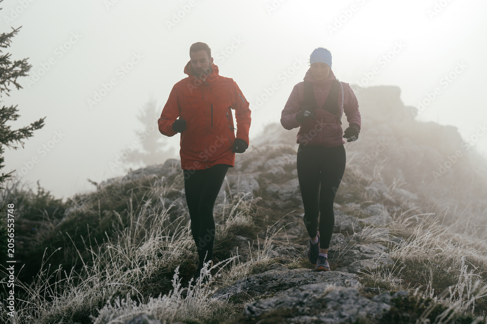 Obraz premium Trail running couple man and woman running on a mountain path
