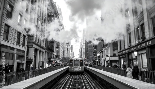 Black and White Subway Train Approaching Central Tracks in Busy City Street