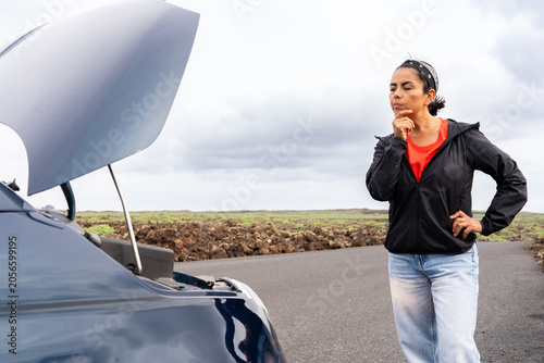 Fotografia Woman experiencing car breakdown on a rural road, thinking about the vehicle eng