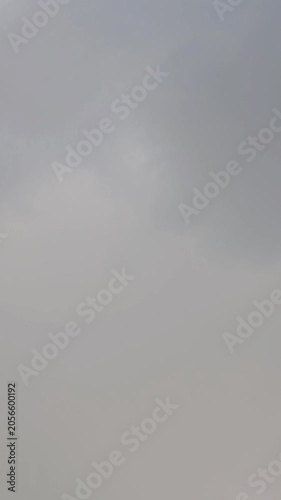 Vertical video of a lightning flash in dark gray storm clouds. Dramatic thunderstorm sky, atmospheric weather phenomenon and natural electricity during overcast conditions.