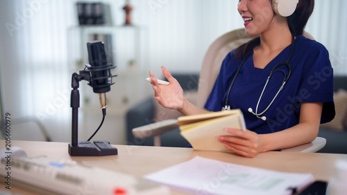Cuadro en lienzo Asian female doctor wearing headphones and stethoscope recording educational pod