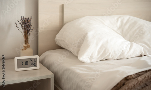 Soft morning light on unmade bed with white pillows and clean bedding in a minimalist bedroom. Cozy home interior with comfortable sleeping space.