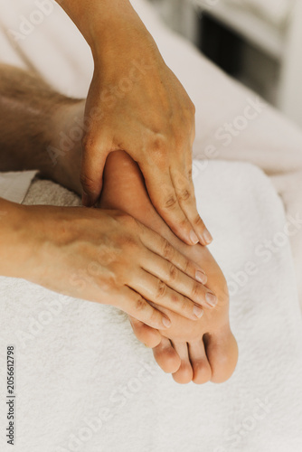 Close up of foot massage therapy session. Female massage therapist's hands.
