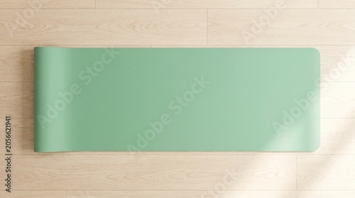 Top-down flat lay view of a minimalist sage green yoga mat unrolled on a light wooden floor