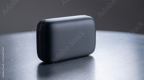 A sleek minimalist matte black electronic device case standing on a brushed metal surface