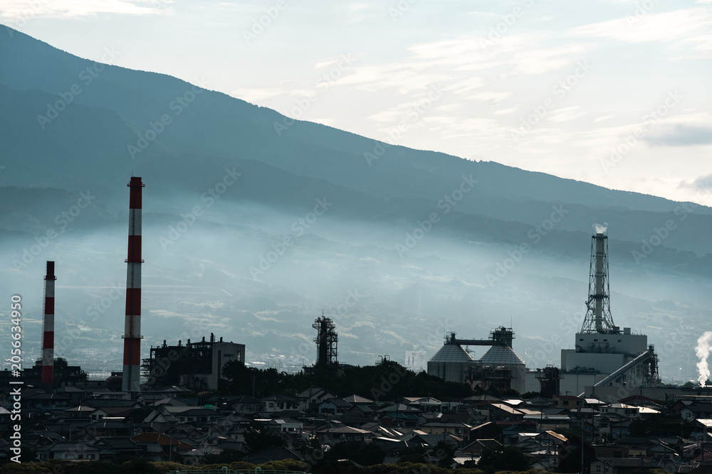 Obraz premium Industrial factory smokestack mountain fog city chimney pollution landscape plant industrial factory with smokestack near mountain slope, fog over city skyline, chimney tower, pollution haze