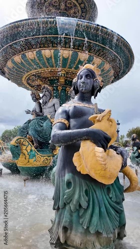 Ornate bronze sea god sculptures decorate baroque fountain in central Paris square
