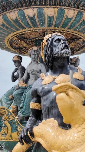 Ornate bronze sea god sculptures decorate baroque fountain in central Paris square