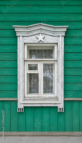 Window of a very old Russian house with a carved frame and a five-pointed star