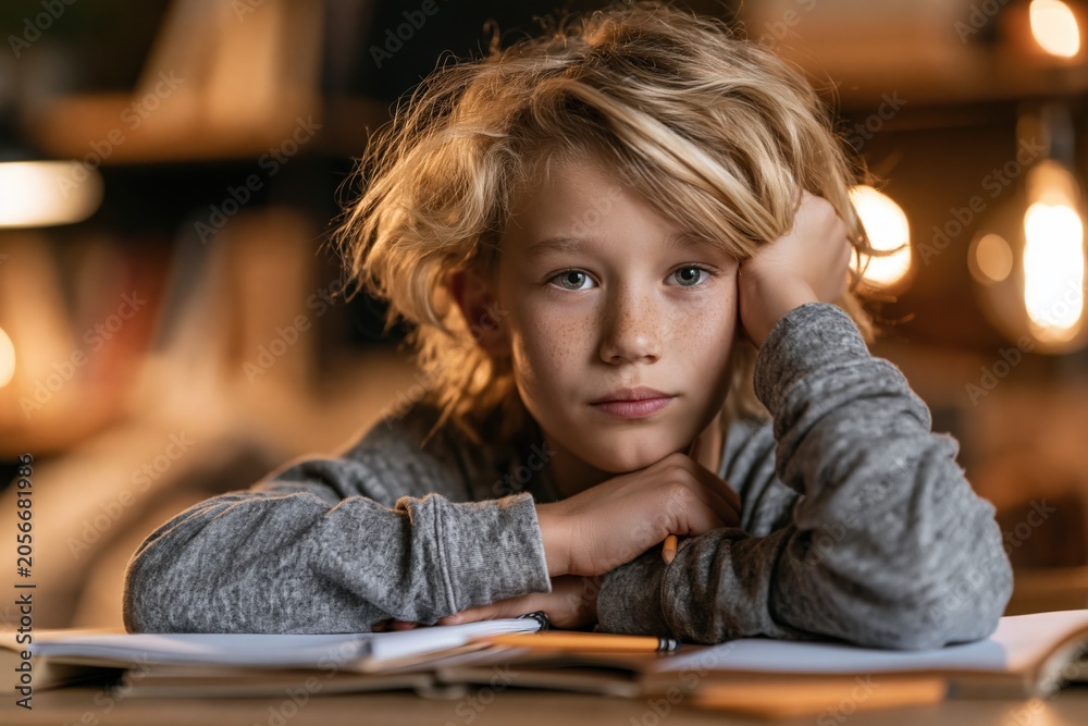 Fototapeta Young boy rests arms on open books