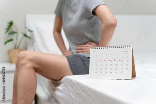 Cuadro en lienzo Close-up of period calendar on bed with blur woman holding her stomach in pain, menstrual cramps or PMS symptom concept