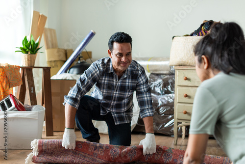 Photography Couple moving rug together indoors