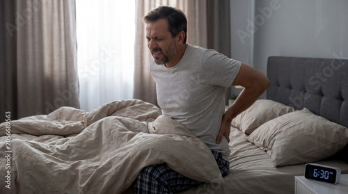 man suffering from back pain from bad night sleep