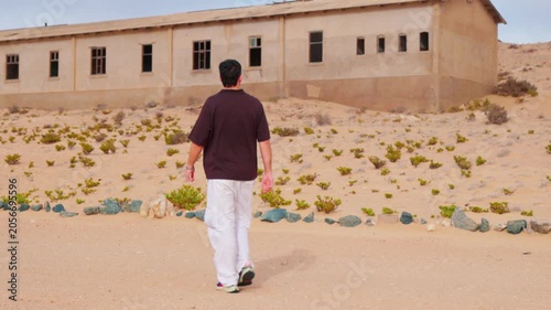 Male tourist walking through the abandoned ghost town of Kolmanskop