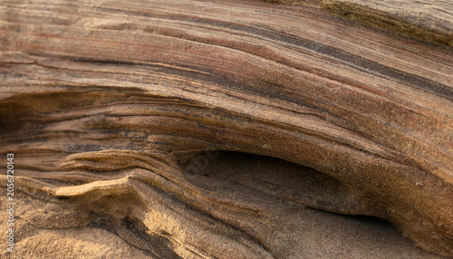 Natural weathered sandstone rock surface showing intricate erosion patterns and earthy brown sediment layers with sandstone sedimentary background formation geological material abstract