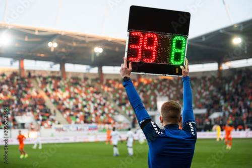 Bild auf Leinwand Rear view of a fourth official holding an electronic substitution board showing numbers 39 and 8 at a football stadium