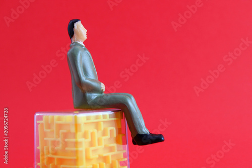 Photos Executive sitting on a cube with a maze of problems