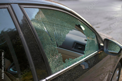 Broken side window of parked car. Vehicle vandalism and insurance claim concept.