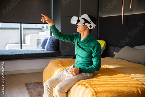 White VR headset resting on bed, green sweater and smartwatch catching daylight from window