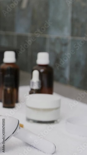 Vertical video: Panning cam zooming on cream jar, amber bottles and tool at sink, showing tiles