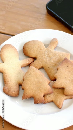 Vertical video: Shifting camera centering white plate of four cookies at home showing smartphone