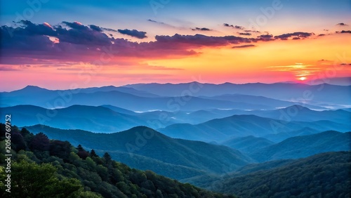 Dramatic sunset over layered mountain ranges with hazy atmospheric perspective