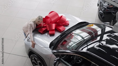 Woman Leaning on New Car with Red Bow in Dealership