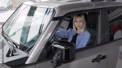 Happy business woman sitting in new car at dealership showroom