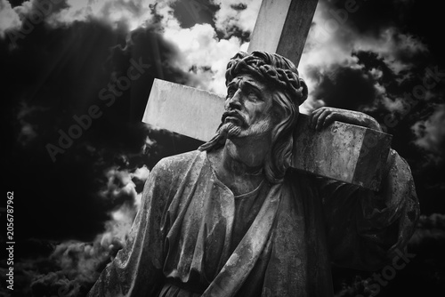 Jesus Christ carrying the cross under a dramatic sky