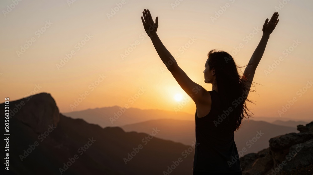 Fototapeta premium Woman raising arms watching sunset from mountain overlook during golden hour