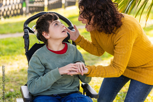 Mother comforting her son with disability in wheelchair in a park