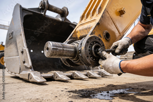 Foto Heavy machinery mechanic performing maintenance on excavator bucket pivot joint