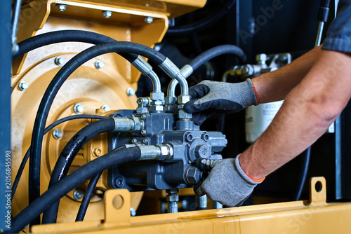 Fotografía Mechanic wearing gloves works on heavy machinery hydraulic system components