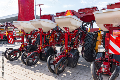 Fotografie Multiple red tractor-mounted seed planters lined up outdoors on a paved surface
