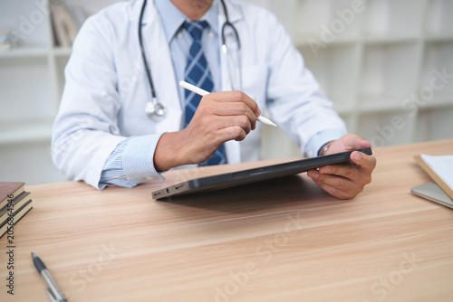 Healthcare Professional Using Tablet for Digital Record Keeping in Medical Office Setting
