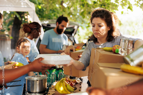 Slika na platnu Diverse group provides aid, handing out meals to poor and needy individuals, with volunteers of all backgrounds come together to help the homeless, offering support through a charitable food drive