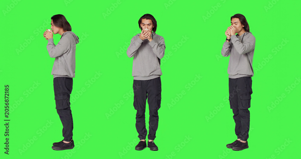 Obraz premium Person drinking coffee on camera, holding cup of hot caffeine beverage over full body green screen template, with young man enjoying refreshment and feeling positive in studio.