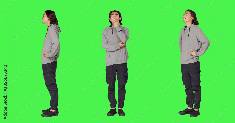 Obraz premium Young man feeling sleepy and yawning after not getting enough sleep, posing with fatigue over full body green screen backdrop, with person being extremely tired and exhausted, falling asleep.