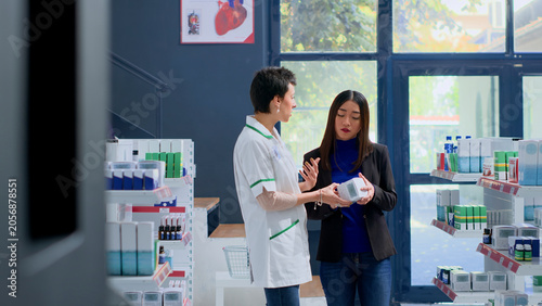 Fotografía Shopper in pharmacy needing prescription drug to calm nausea feeling, asking pharmacist to help her pick best medicament, with knowledgeable pharmacologist assisting customer with product counsel