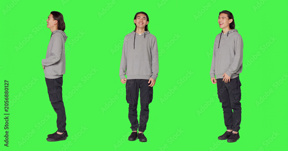 Obraz premium Cheerful male model laughing in studio, posing and being positive against full body green screen backdrop.