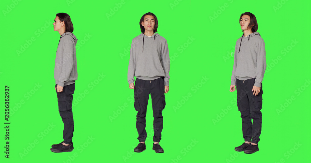 Obraz premium Proud person standing in studio and posing with confidence, acting joyful against full body green screen backdrop, with young smiling man being optimistic and friendly in casual clothes.