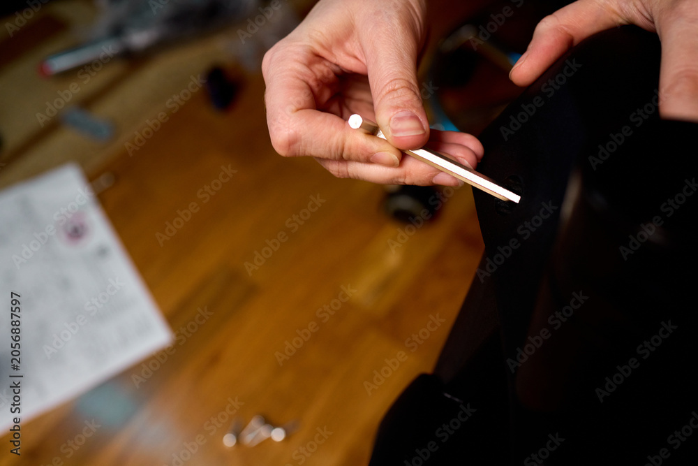 Obraz premium Close-up of hands repairing textured black fabric seat in workshop