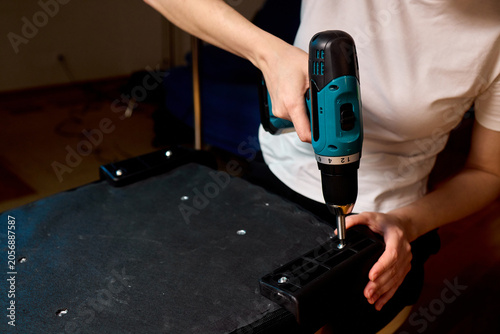 Person using cordless drill to assemble upholstered furniture