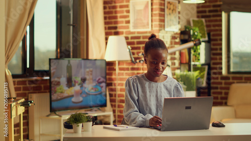 Obraz na płótnie African American worker begins work day at home workstation, starting to solve daily tasks at sunset, woman freelancer being self employed and feeling pleased with online career