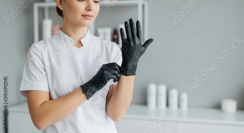 Beautician Wearing Black Gloves Preparing for Client Treatment in Spa.